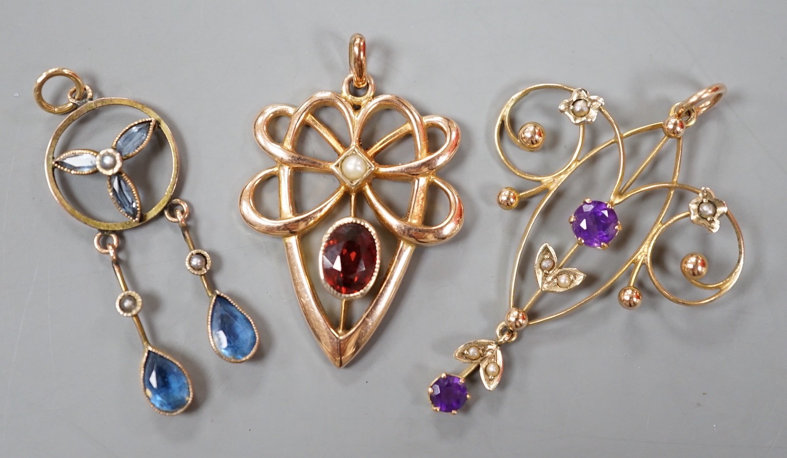 Three assorted early 20th century yellow metal and gem set pendants, including 9ct garnet and split pearl, largest overall 39mm, gross weight 5.2 grams.